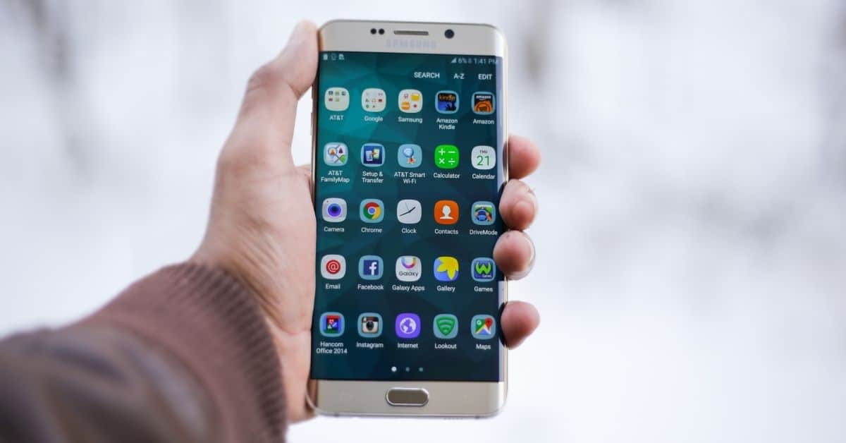 Изображение на ръка, държаща телефон с Android, на чийто екран се виждат множество приложения за транскрипция.